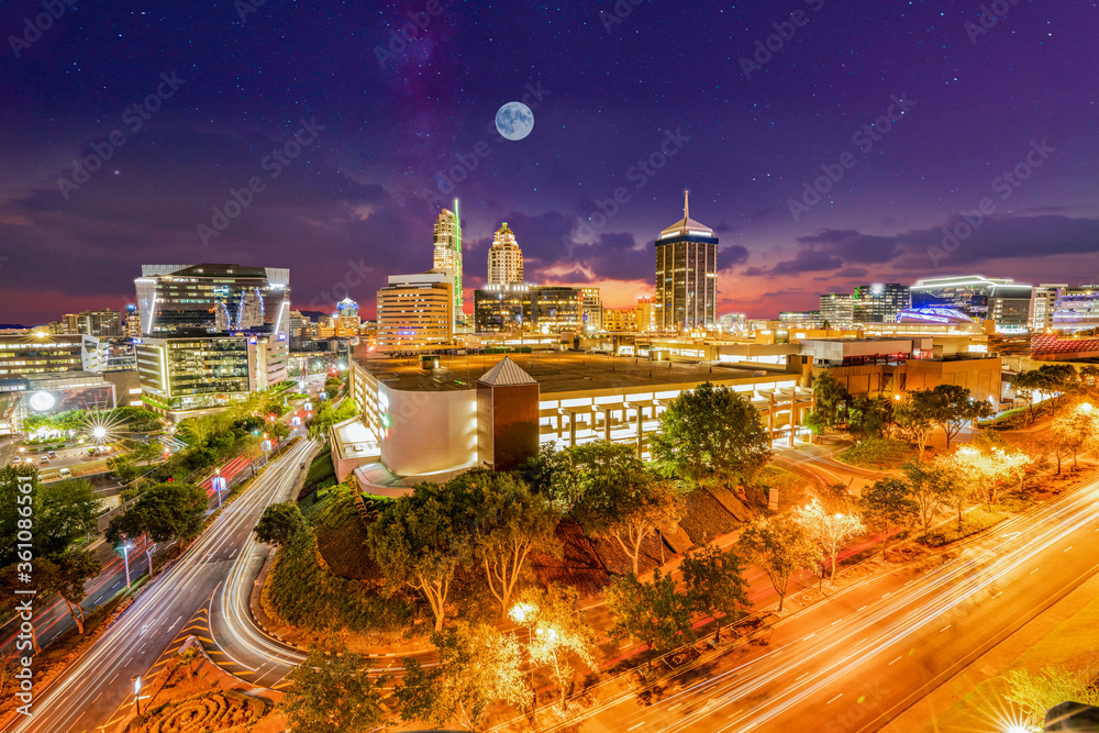 Fototapeta premium Sandton City at night illuminated buildings with moon and stars in the sky