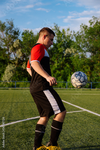 Young male soccer player juggles a ball on a soccer field © bo.kvk