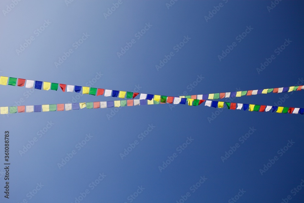 Bright colorful buddhist Prayer flags on clear blue sky background. Multi colored Prayer flags in Himalaya mountains. Buddhist symbols. Freedom. Meditation. Zen-like backgrounds. Flags in the sky. Bright colorful buddhist Prayer flags on clear blue sky background. Multi colored Prayer flags in Himalaya mountains. Buddhist symbols. Freedom. Meditation. Zen-like backgrounds. Flags in the sky.
