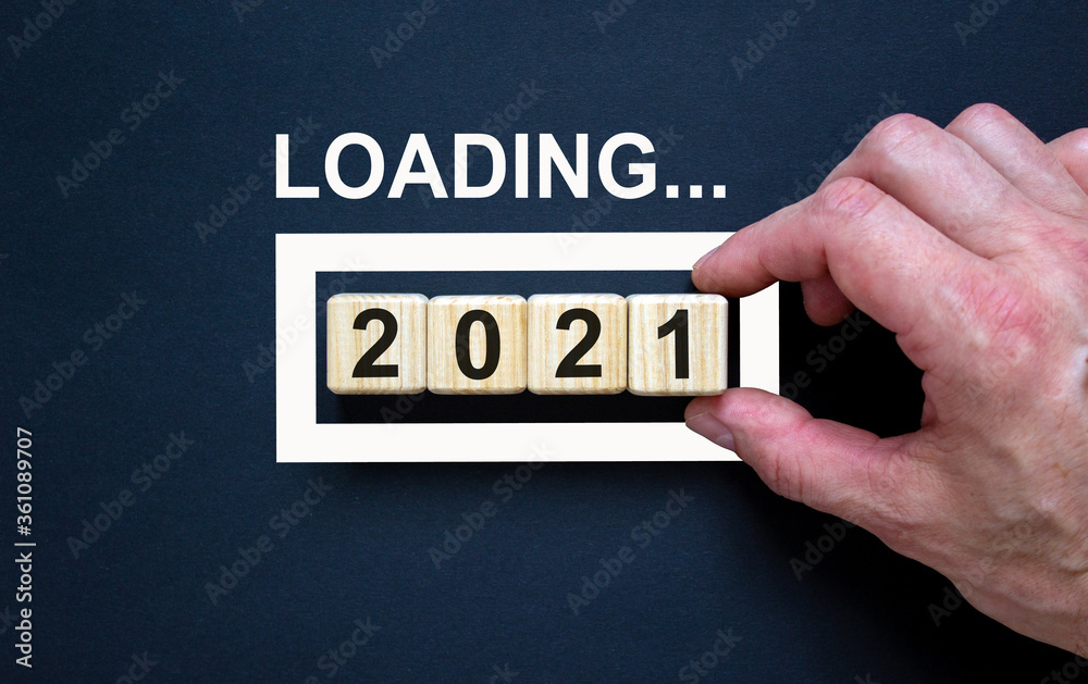 Loading new year 2021 with hand putting wood cube in progress bar. Business concept. Loading new year 2021 with hand putting wood cube in progress bar. Business concept.