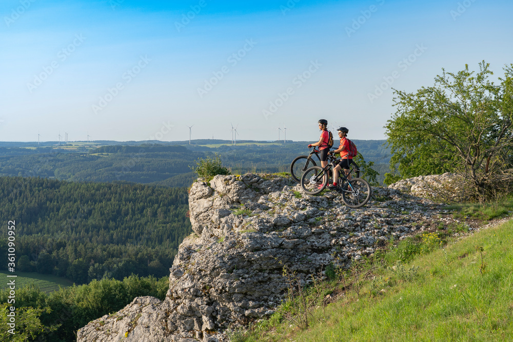 Grandmother and granddaughter riding their mountainbikes in the rocky landscape of Frankonian Switzerland in Bavaria, Germany