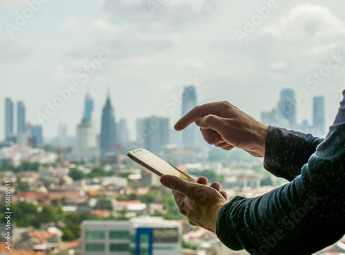A man uses a phone against the backdrop of a panorama of a metropolis.