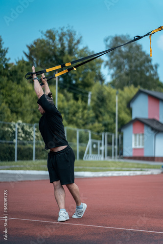 young sporty athlete or bodybuilder has fitness workout with trx outdoor © goami