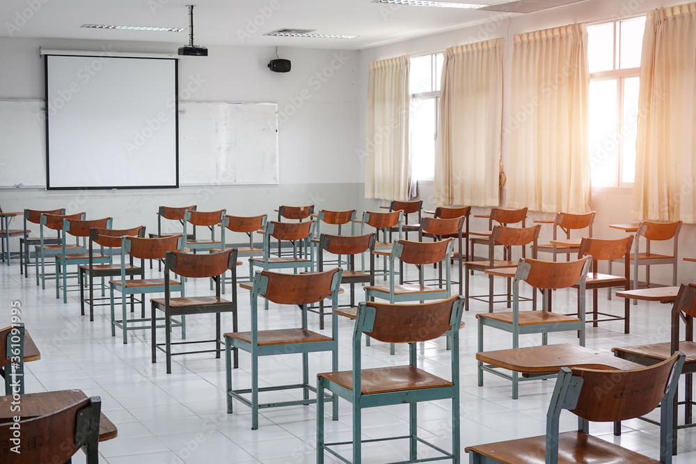 Empty classroom with vintage tone wooden chairs. Classroom arrangement in social distancing concept to prevent COVID-19 pandemic. Back to school concept.	