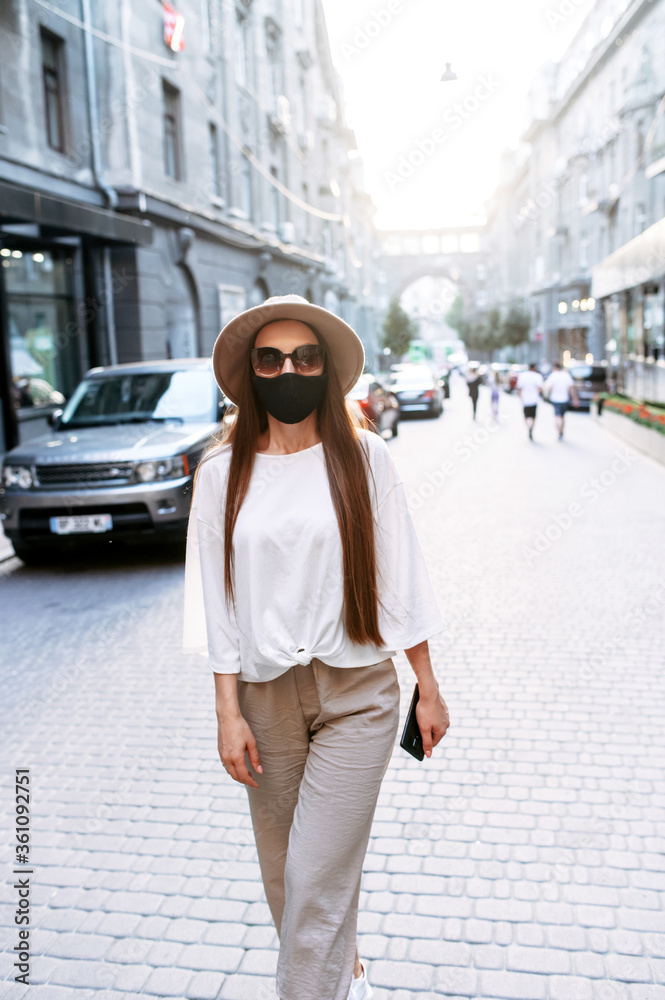 Obraz premium Young woman in medical mask is walking around the city. Protecting from allergy, virus, smog