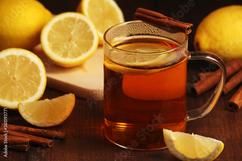 A mug with hot tea with lemons and cinnamon sticks