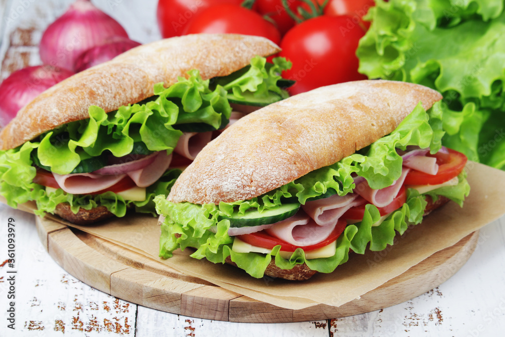 Two sandwiches with fresh vegetables, ham and cheese in ciabatta bread Two sandwiches with fresh vegetables, ham and cheese in ciabatta bread