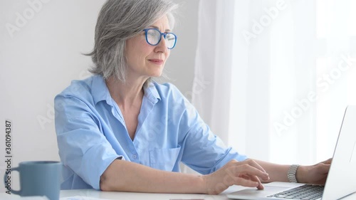 Wallpaper Mural Mature lady in glasses using laptop, watching photos or reading morning news Torontodigital.ca