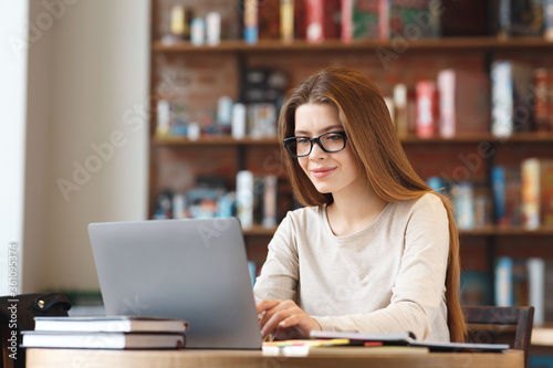 Smiling brunette woman working on laptop in cafe