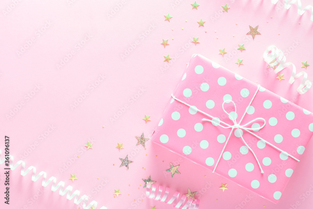 Gift box on pink background with copy space and lots of confetti. Gift wrapped in pink polka dot paper. Gift box on pink background with copy space and lots of confetti. Gift wrapped in pink polka dot paper.