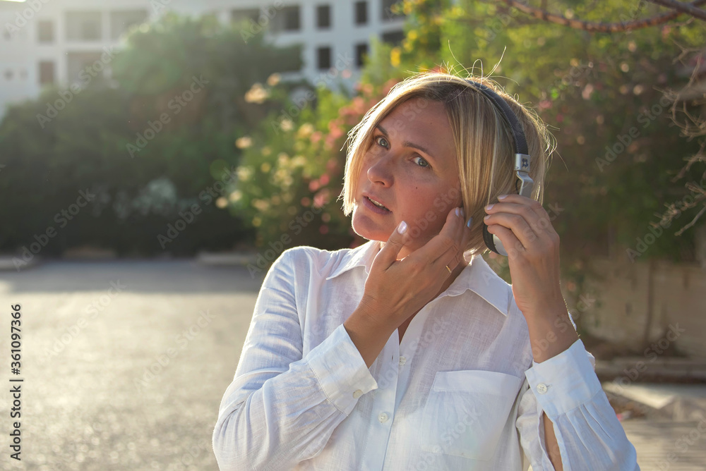 A portrait of woman with short hair with headphone feeling ear pain outdoor A portrait of woman with short hair with headphone feeling ear pain outdoor