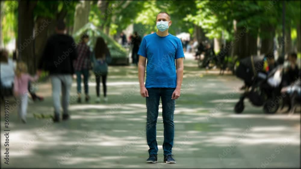 Timelapse of Man Stands Still in Medical Face Mask on Crowded Walkway Park Boulevard Summer Day. People Moves Fast. Concept of Flowing Time and Life in Quarantine While Spreading Pandemic in the World Timelapse of Man Stands Still in Medical Face Mask on Crowded Walkway Park Boulevard Summer Day. People Moves Fast. Concept of Flowing Time and Life in Quarantine While Spreading Pandemic in the World