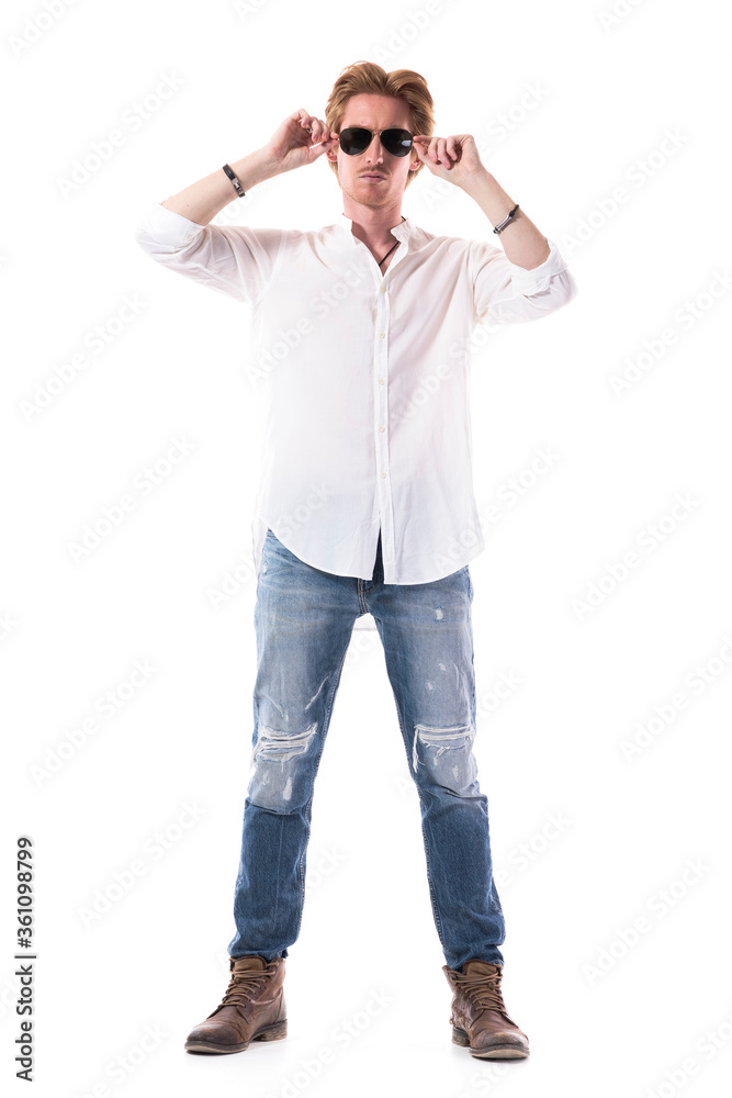 Macho confident stylish handsome ginger man putting on sunglasses looking at camera. Full length portrait isolated on white background. Macho confident stylish handsome ginger man putting on sunglasses looking at camera. Full length portrait isolated on white background.