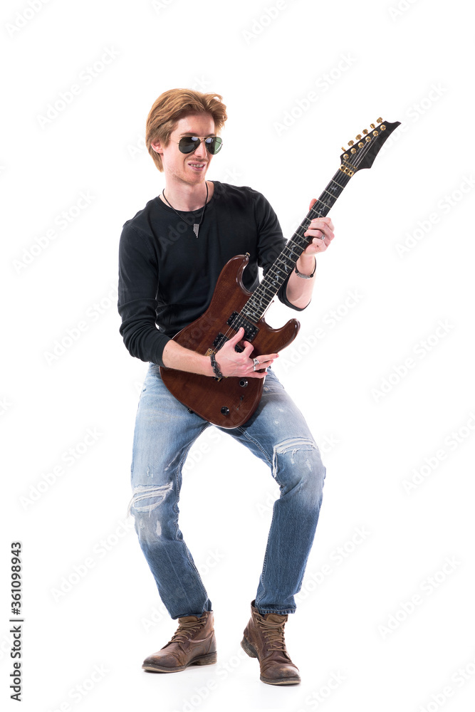 Young happy smiling handsome stylish rocker playing electric guitar looking away. Full length portrait isolated on white background. Young happy smiling handsome stylish rocker playing electric guitar looking away. Full length portrait isolated on white background.