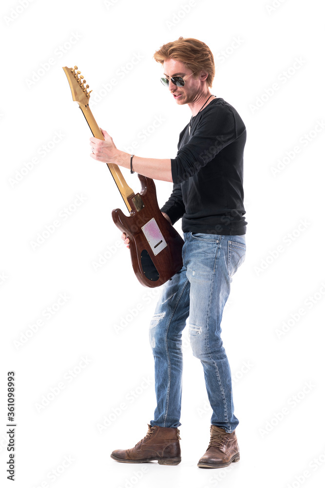 © sharplaninac - Side view of talented passionate rock and roll guitarist playing electric guitar. Full length portrait isolated on white background.