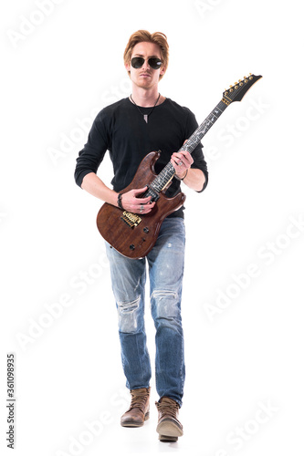 Handsome young red hair rocker stepping forward playing electric guitar. Full length portrait isolated on white background.  © sharplaninac