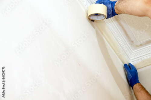 Man plastering a white wall preparing it for painting or wallpapering in a DIY and home decoration or renovation concept.