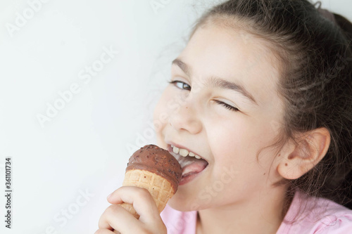 Happy little kid girl eating ice cream indoors