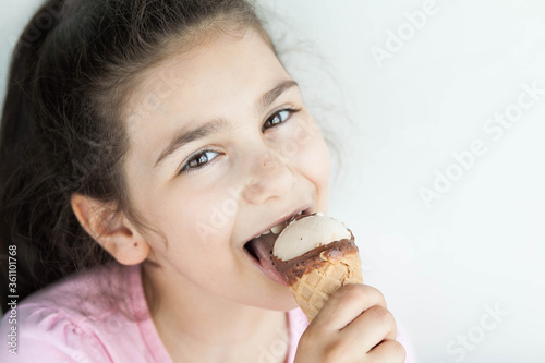 Happy little kid girl eating ice cream indoors