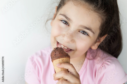 Happy little kid girl eating ice cream indoors