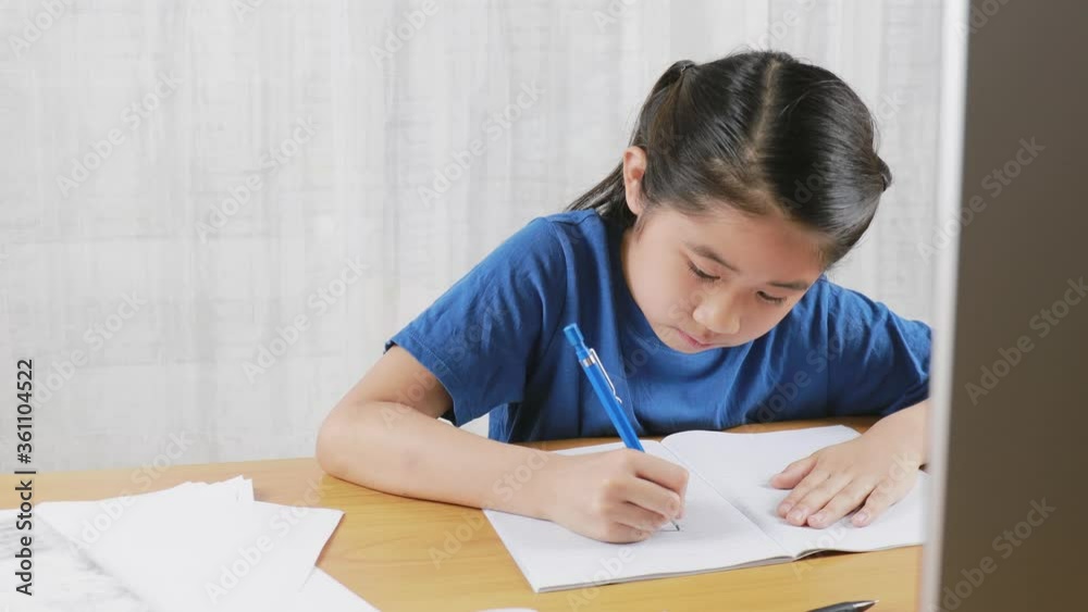 4K UHD Asian little girl is studying online via the internet sitting and writing in living room at home. Asia children writh with pencil on notebook. online learning at home or learn home concept. 4K UHD Asian little girl is studying online via the internet sitting and writing in living room at home. Asia children writh with pencil on notebook. online learning at home or learn home concept.