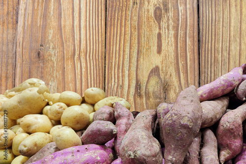 Sweet potato and English potato on aged wooden background
