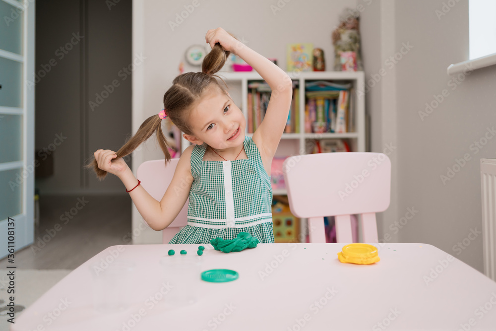 Little girl with a lovely face play with clay molding shapes, learning through playing with colored plasticine developing creativity Little girl with a lovely face play with clay molding shapes, learning through playing with colored plasticine developing creativity