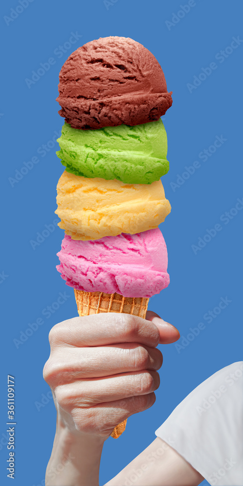 Hand holding ice cream scoops in cone on blue sky background including