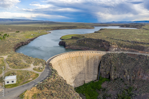 Fron large view of an arch gravity dam across lava canyon cutting into a plateau, creating a reservoir behind, a road crossing the top, Salmon Falls Dam, Idaho