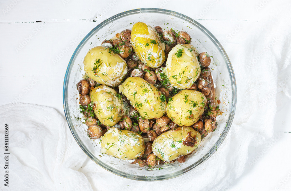 Roasted young potatoes in glass baking dish with mushrooms.