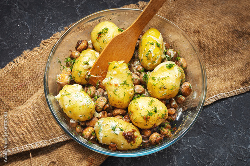 Bild auf Leinwand Roasted young potatoes in glass baking dish with mushrooms