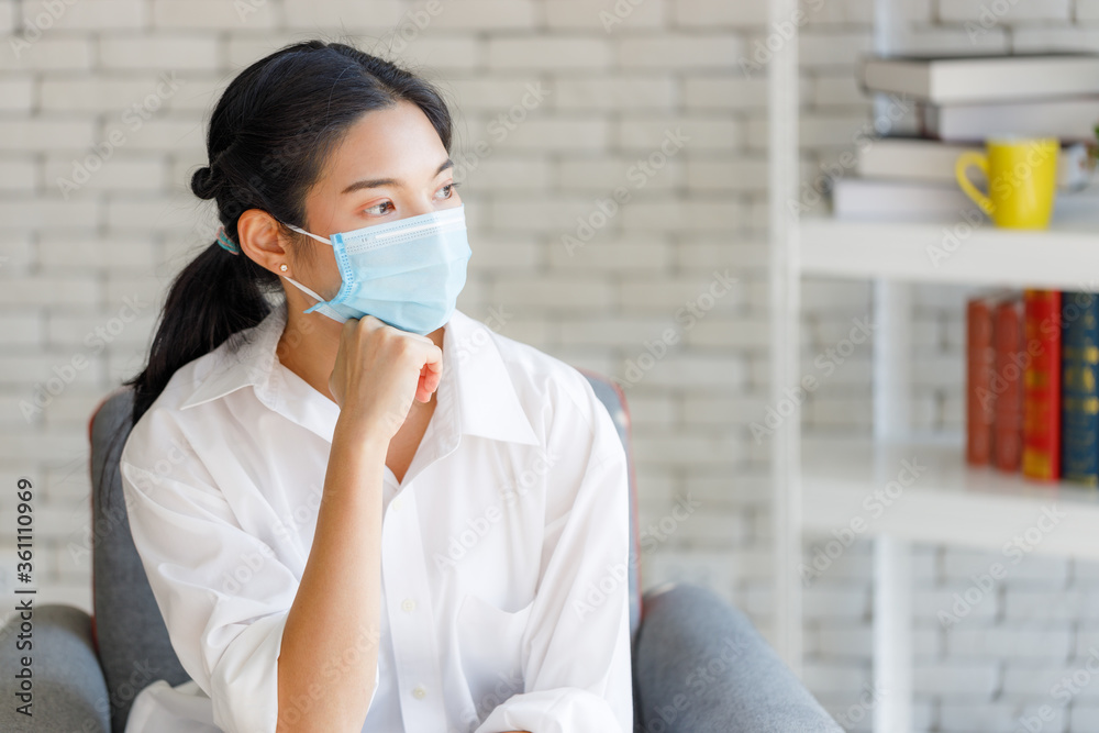 Young Asian woman wearing masks is worried as she is quarantined to the house during the outbreak of the COVID 19 virus. Young Asian woman wearing masks is worried as she is quarantined to the house during the outbreak of the COVID 19 virus.