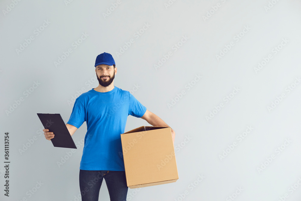 Deliveryman holding clipboard and carton parcel box with space for design on grey background. Online postal service Deliveryman holding clipboard and carton parcel box with space for design on grey background. Online postal service