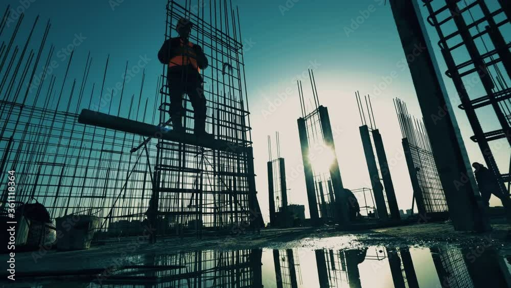 Construction industry, construction project, building process during sunset. Constructors are building a metal framework of a building