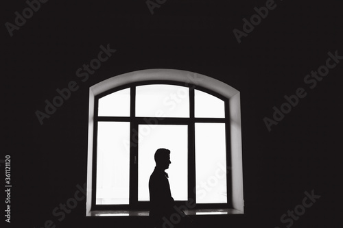 Silhouetted men on the background of an arched window.  © dimadasha