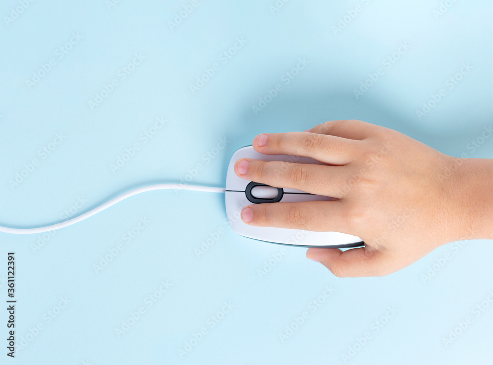 Child's hand holds a computer mouse on a blue background. Child's hand holds a computer mouse on a blue background.