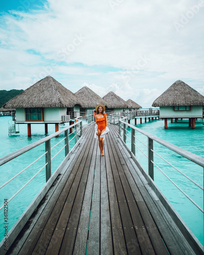 beautiful girl in swimsuit posing on dock, tropical resort in background