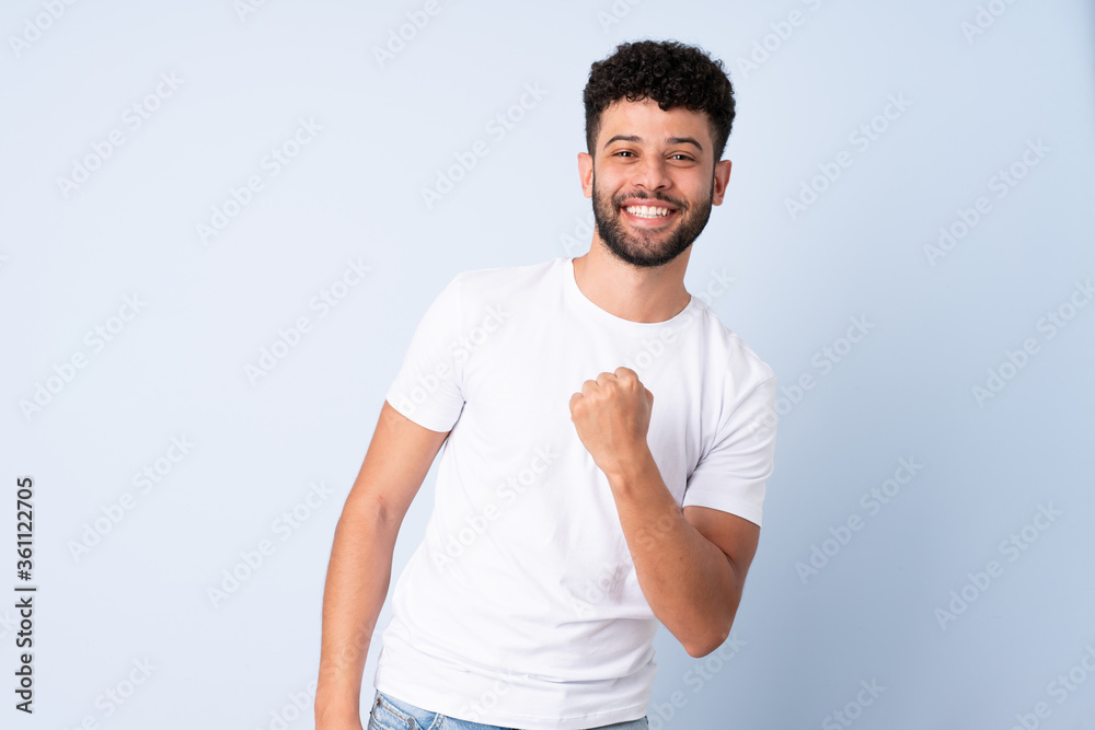 Young Moroccan man isolated on blue background celebrating a victory Young Moroccan man isolated on blue background celebrating a victory