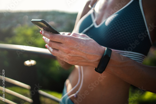 Female hands typing on mobile phone while exercising