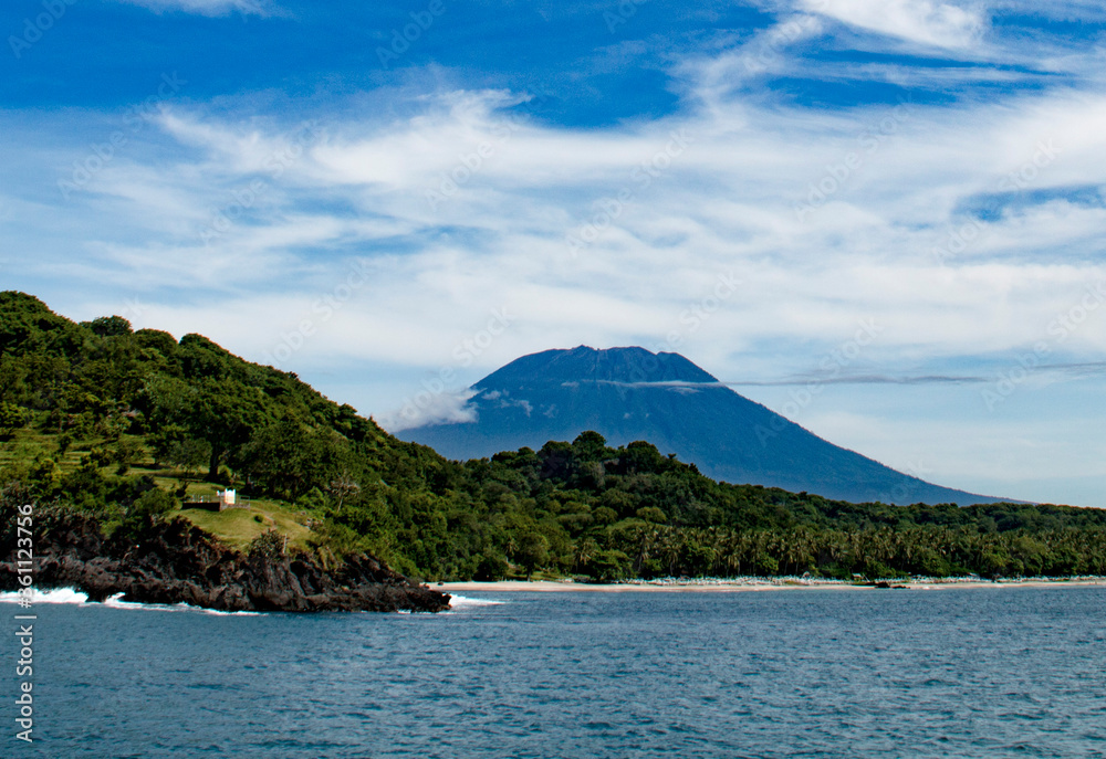 View of Agung volcano on a sunny day against the backdrop of a green rainforest from Gili Island, Indonesia