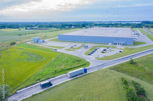 Aerial view of goods warehouse. Logistics center in industrial city zone from above. Aerial view of trucks loading at logistic center. View from drone.