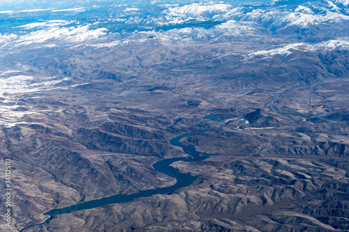 Aerial View of Idaho mountains and snake river from the sky while inside an airplane. View of brown mountains and trees covered with snow