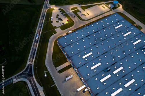 Fototapeta Naklejka Na Ścianę i Meble -  Night Aerial view of goods warehouse. Logistics center in industrial city zone from above. Aerial view of trucks loading at logistic center