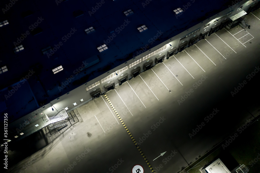 Night Aerial view of trucks unloading in logostics center. Logistics center in industrial city zone from above. Aerial view of trucks loading at logistic center Night Aerial view of trucks unloading in logostics center. Logistics center in industrial city zone from above. Aerial view of trucks loading at logistic center