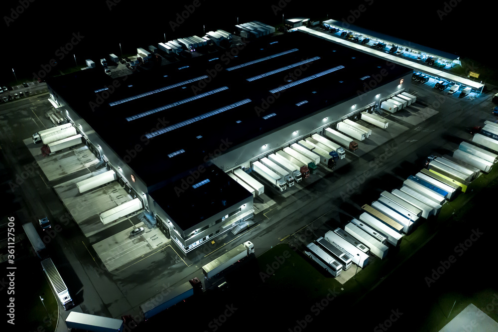Night Modern logistics center, white van and trailers standingon ramp. Aerial View