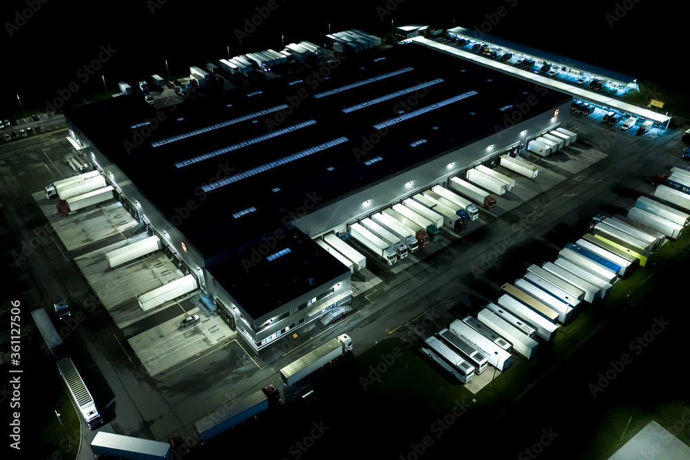 Night Modern logistics center, white van and trailers standingon ramp. Aerial View Night Modern logistics center, white van and trailers standingon ramp. Aerial View
