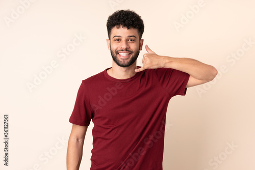 Young Moroccan man isolated on beige background making phone gesture. Call me back sign © luismolinero