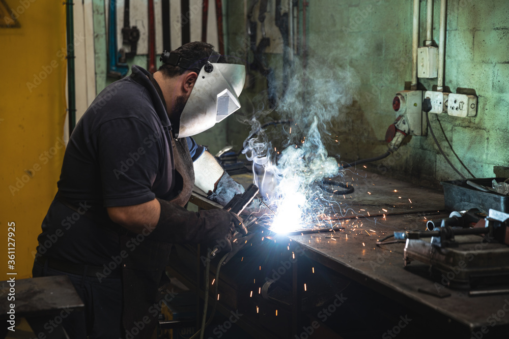 Male factory worker wearing mask welding at the factory Male factory worker wearing mask welding at the factory