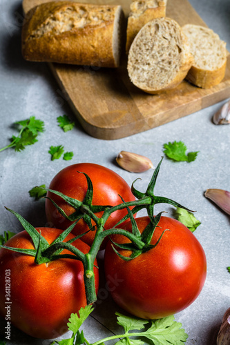 Three tomatoes with bread in the background on a gray stone