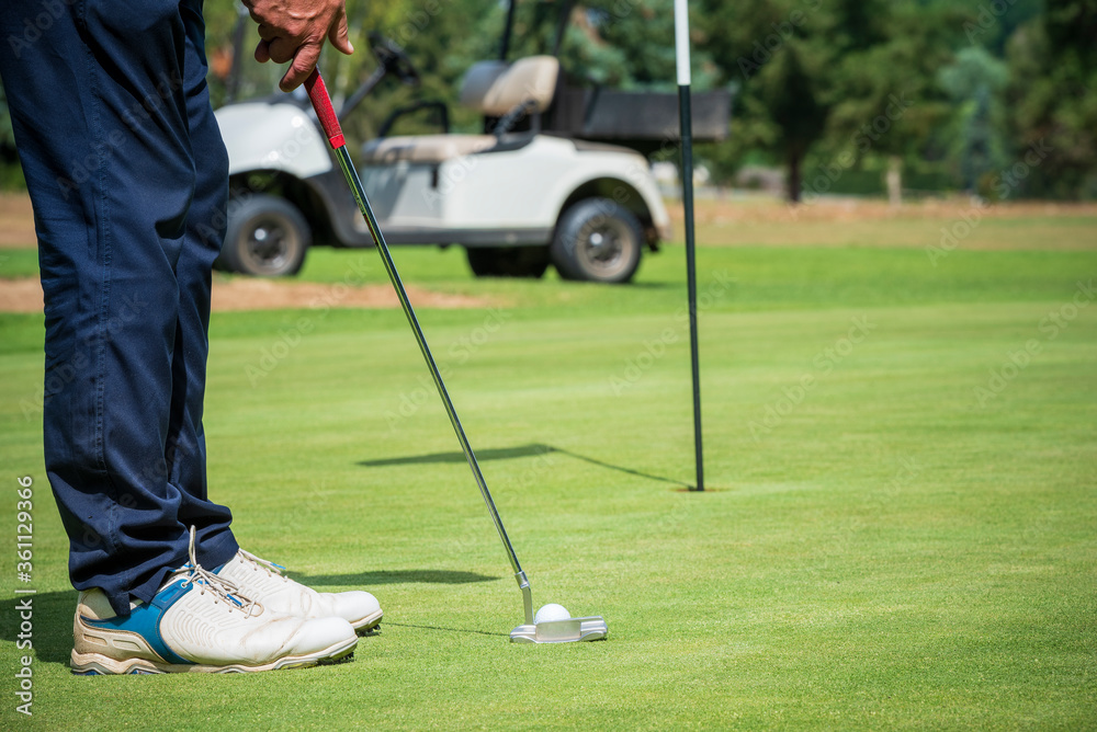 Obraz premium Golfeur avec putter et voiture de golf